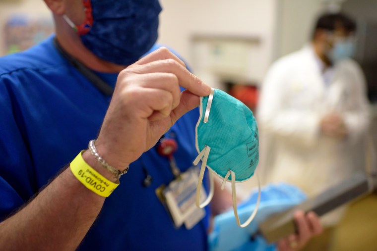 A person holds up an N95 mask in the ER at a medical center in Richmond, Texas
