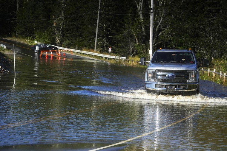 A motorist travels through flood waters in Northeast Harbor, Maine