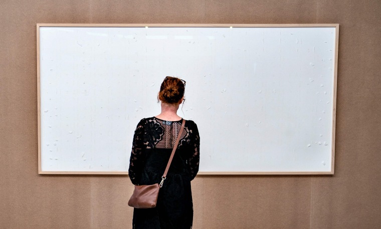 A woman stands in front of an empty frame hung up at the Kunsten Museum in Aalborg, Denmark
