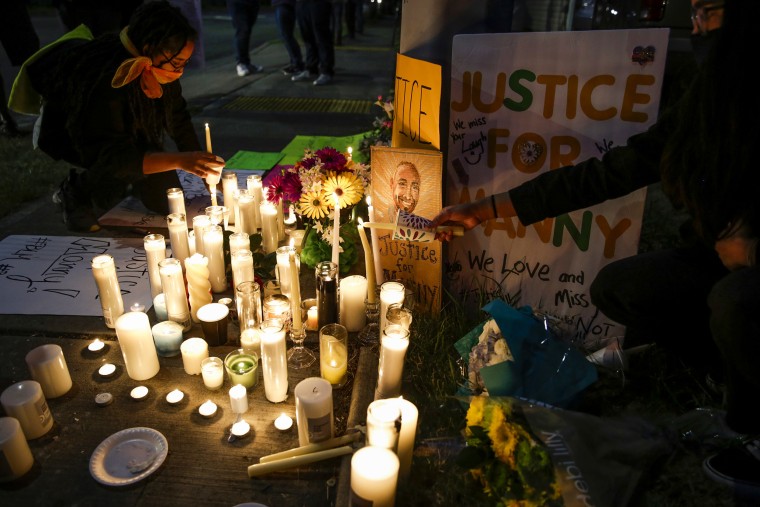 People light candles at a makeshift memorial on June 3, 2020, at the intersection where Manuel Ellis died in Tacoma Police custody.