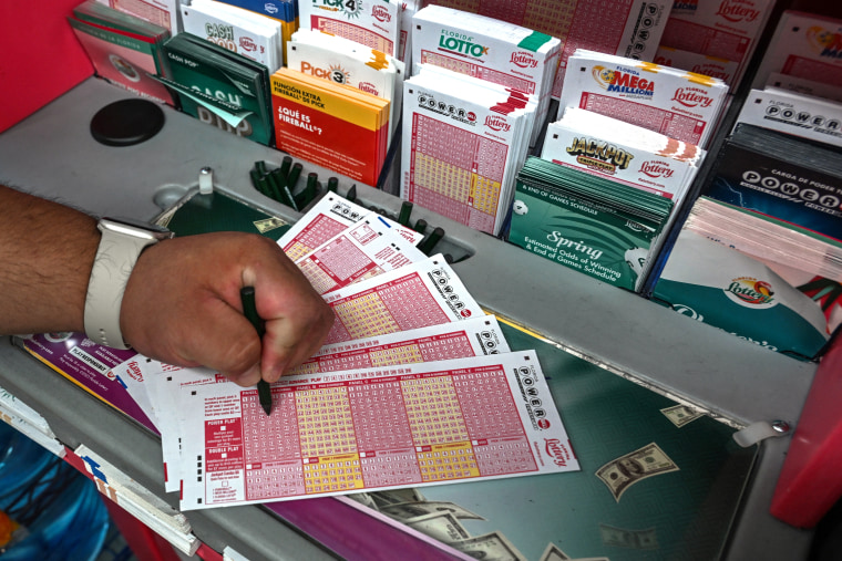 A woman fills in Powerball lottery tickets inside a store