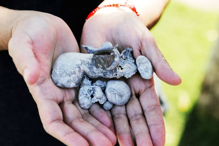 Gabriella Miyamoto is holding some melted metal that Erwin found near where her jewelry box would be in her bedroom. They think it could be melted jewelry. She is also holding a ring that belongs to Erwin. It has a figure of a chicken on it.