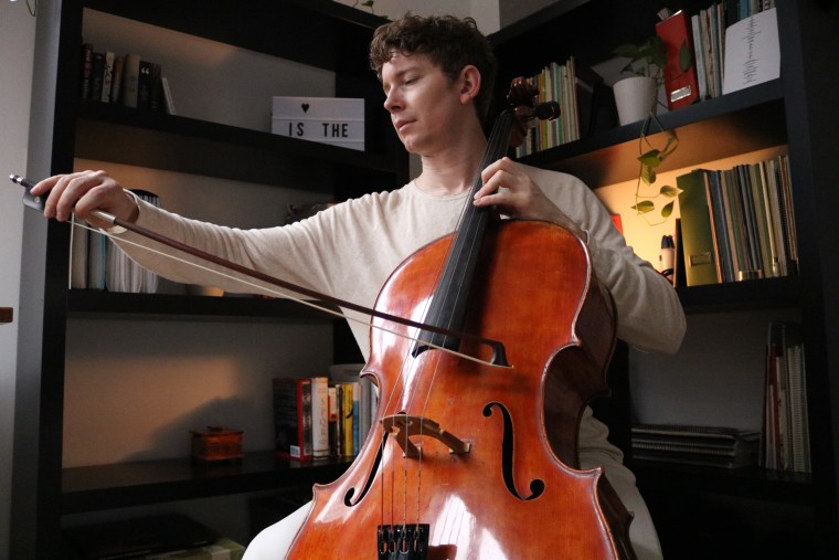 Joshua Roman practices the cello at his New York City home on Sunday. Long Covid left Roman with uncontrollable trembling, threatening his career.