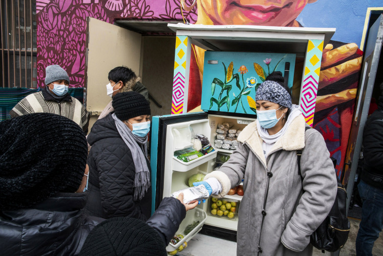 Volunteers pass out information on the Covid-19 vaccine as people receive food from the 24-hour community fridge at the Mixteca community center in Brooklyn, N.Y., on Feb. 13, 2021.