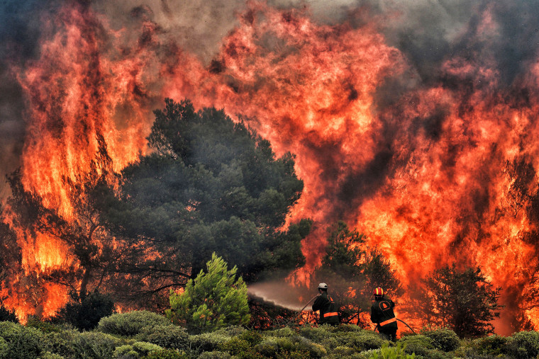 Firefighters try to extinguish flames during a wildfire at the village of Kineta, near Athens, on July 24, 2018. - Raging wildfires killed 74 people including small children in Greece, devouring homes and forests as terrified residents fled to the sea to escape the flames, authorities said Tuesday. 