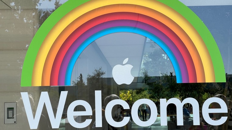 Una ventana en las oficinas de Apple en Cupertino, California, en 2022 con una decoración de vinilo de un arcoíris, el icono de la manzana de la marca y la palabra "Bienvenidos" en inglés.
