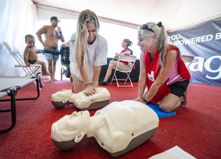 Samantha Ly (izquierda), aprende técnicas de reanimación cardiopulmonar de Susan McClaran, una voluntaria del equipo de emergencias de Huntington Beach, California, el 1 de agosto de 2023.