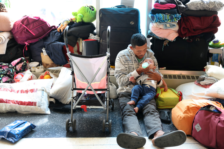 CHICAGO, ILLINOIS - MAY 09: A migrant father from Venezuela feeds his 15-month-old son in the lobby of a police station where they have been staying with other migrant families since their arrival to the city on May 09, 2023 in Chicago, Illinois. Chicago Mayor Lori Lightfoot issued a state of emergency on Tuesday amid a surge in migrant arrivals which began in August 2022 when the first group of immigrants were bused from Texas to Chicago by Texas Gov. Greg Abbott. According to Lightfoot's office, more than 8,000 migrants have arrived in Chicago since last year, with the city currently reaching "a breaking point." About 500 migrants have reportedly been living in the lobbies of police precincts around the city where they sleep on the floors and rely on food donations. (Photo by Scott Olson/Getty Images)