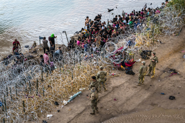 Image: Texas National Guard troops look at immigrants that crossed the Rio Grande into the United States from Mexico