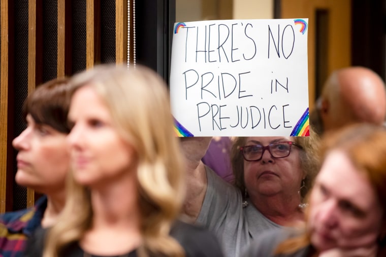 An attendee holds up a sign outside the meeting room during a Grapevine-Colleyville Independent School District school board meeting in Grapevine, Texas on Aug. 22, 2022.