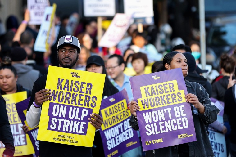 Striking Kaiser Permanente workers hold signs in front of the Kaiser Permanente San Francisco Medical Center.