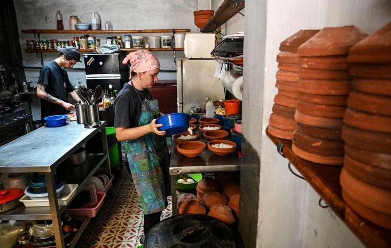 A cook places food in bowls in a kitchen