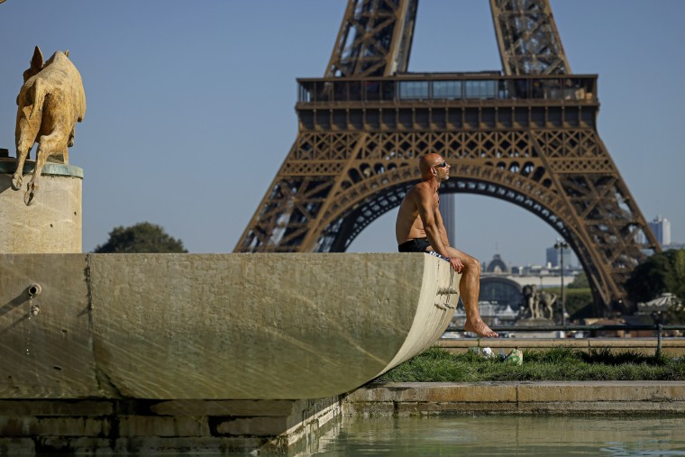 A man sunbathes at the Trocadero fountains in front of the Eiffel Tower on Sept. 7, 2023, in Paris. 