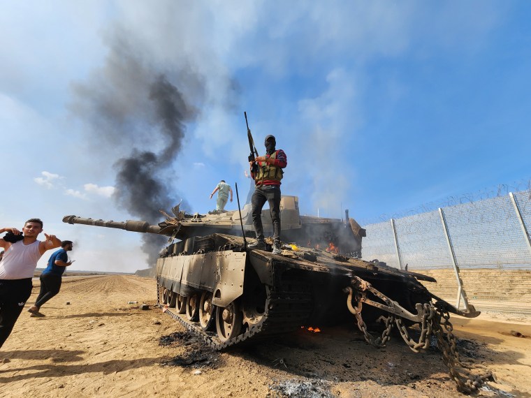 People stand on a burning tank