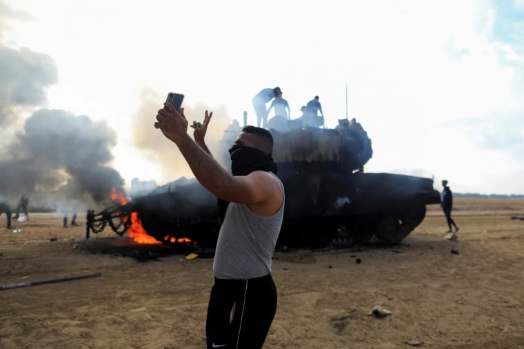 Un palestino se toma una foto frente a un vehículo militar israelí en llamas en el sur de Israel el sábado.