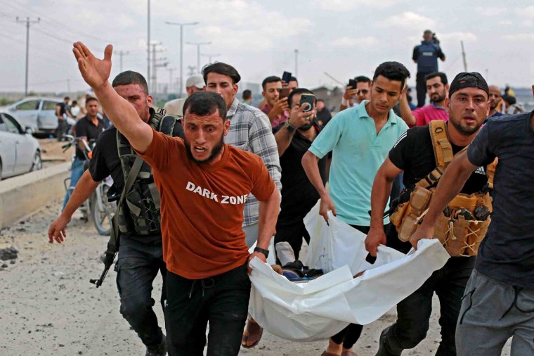 IMage: Palestinian militants carry a victim following an Israeli airstrike at the Erez Crossing at the northern Gaza Strip. Israeli Prime Minister Benjamin Netanyahu said Israel was at "war" with the Palestinian militant group Hamas after the initial attacks.