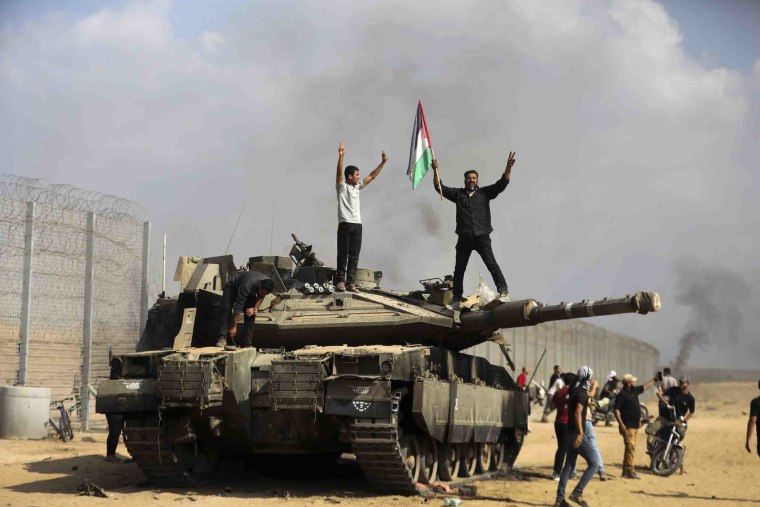 Image: Palestinians celebrate atop a destroyed Israeli tank east of Khan Younis at the Gaza Strip.