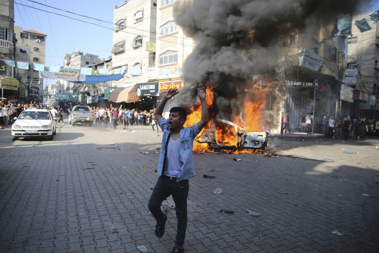 Image: A young Palestinian boy celebrates the burning of an Israeli citizen's car in Beit Lahiya on the Gaza Strip.