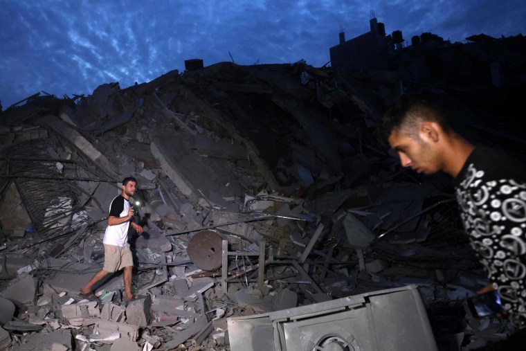 Image: Civilians walk across rubble in Gaza City.