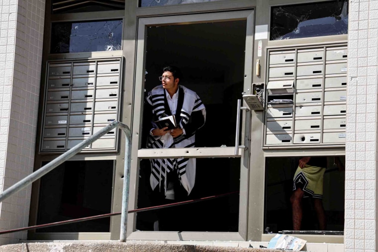 Image: A man in Ashkelon looks out of a damaged building entryway.
