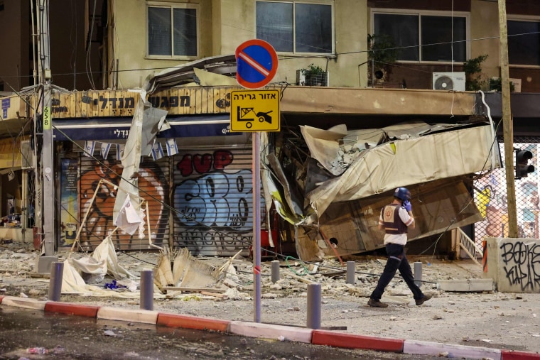 An Israeli rescuer walks in front of a damaged shop in Tel Aviv, after it was hit by a rocket fired by Palestinian militants from the Gaza Strip on October 7, 2023. 