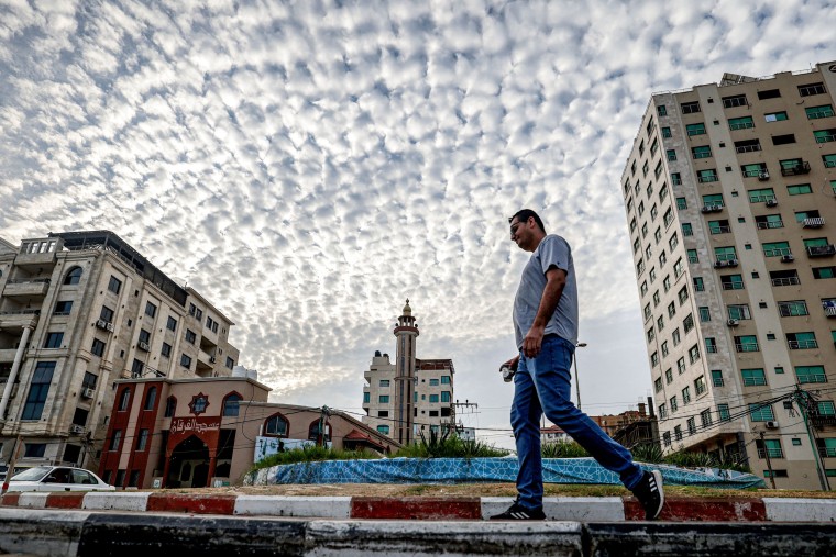 A man takes an early morning walk with a cup of coffee along a street in Gaza City on Oct. 3, 2023. 