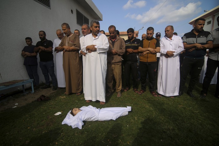 Relatives pray by the body of Amir Ganan, who was killed in an Israeli airstrike, during his funeral in Khan Younis, Gaza Strip, 