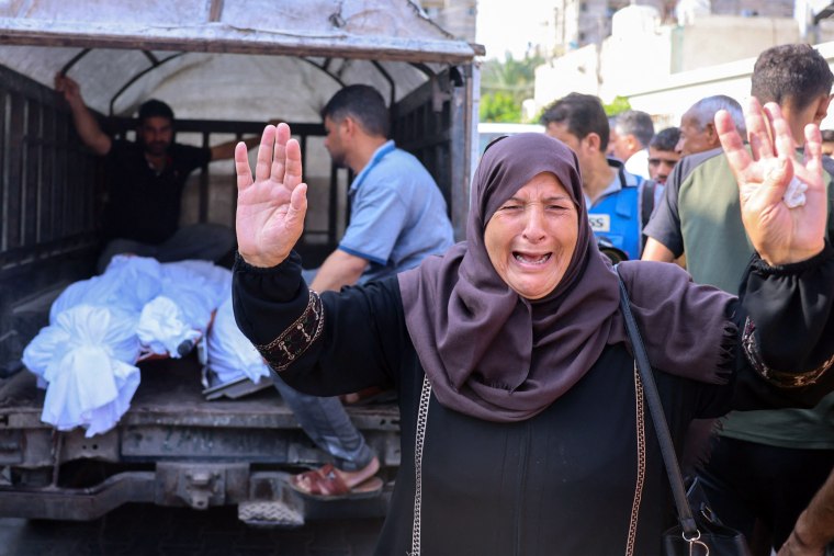 A Palestinian woman reacts as bodies of people killed in overnight Israeli shelling