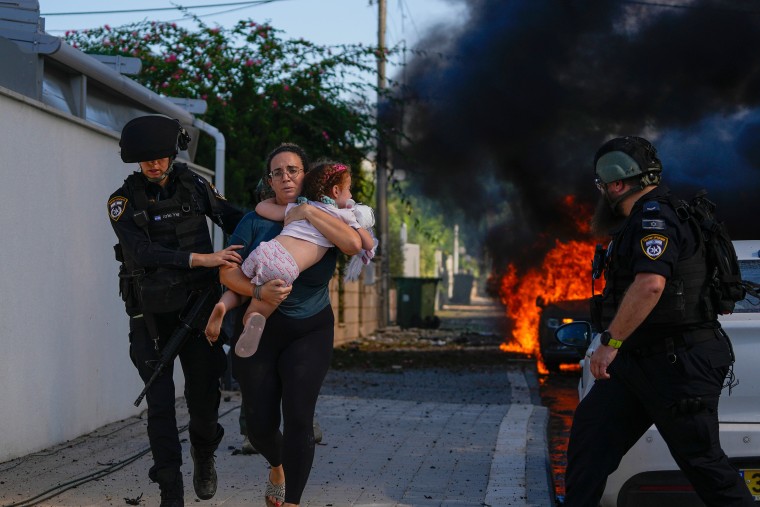 Police officers evacuate a woman and a child from a site hit by a rocket fired from the Gaza Strip in Ashkelon, southern Israel, on Saturday.