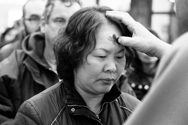 A pastor puts ashes on a woman's forehead.