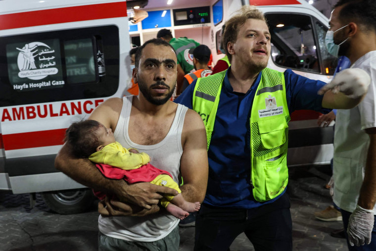 A man brings an injured baby into Al-Shifa hospital in Gaza following an Israeli airstrike.