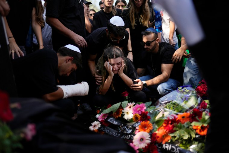 Mourners gather around the grave of May Naim,