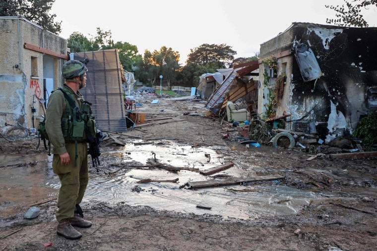 An Israeli troop stands among the rubble of buildings Israeli kibbutz of Kfar Aza