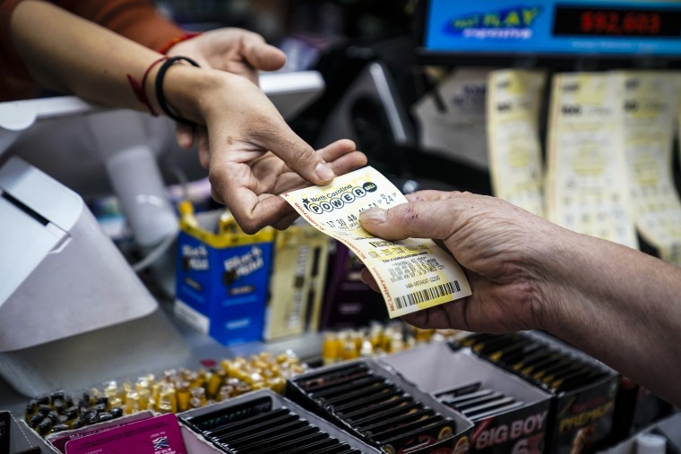 Image: A store manager sells a Powerball ticket at Cigarettes and More on Oct. 4, 2023, in Pineville, N.C.