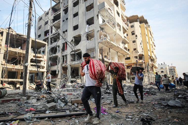 People carry their belongings around destroyed buildings in Gaza City