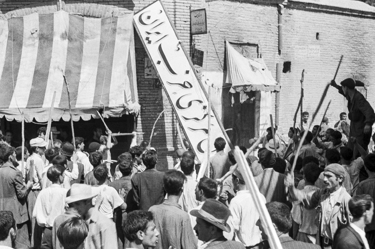 Image: A crowd of demonstrators tear down the Iran Party's sign from the front of the headquarters in Tehran on Aug. 19, 1953
