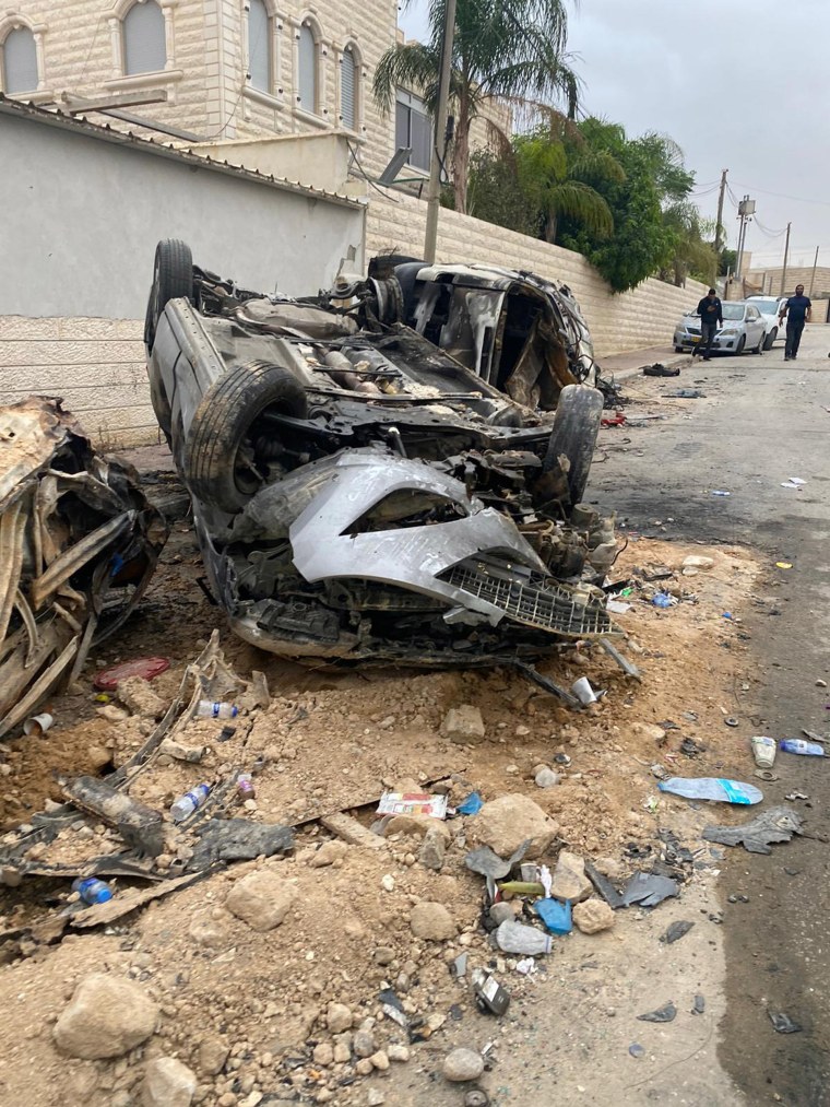 A destroyed car sits in the street from rocket damage in the Bedouin town of Arara.