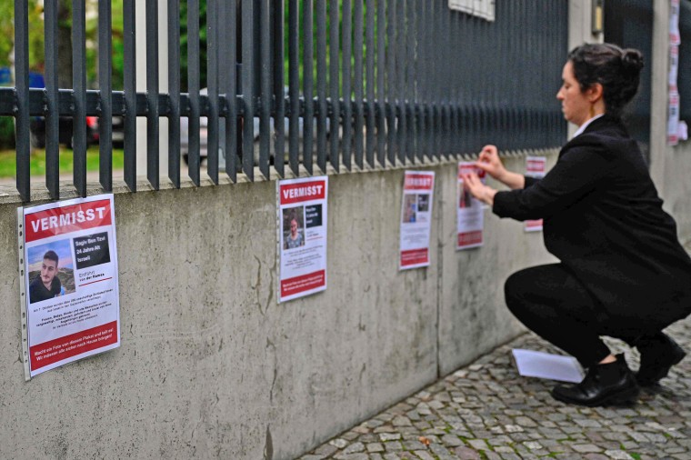 A person hangs posters outside the Synagogue Fraenkelufer in Berlin  on Oct. 13, 2023, with photos of people who went missing following the Hamas attacks in Israel.