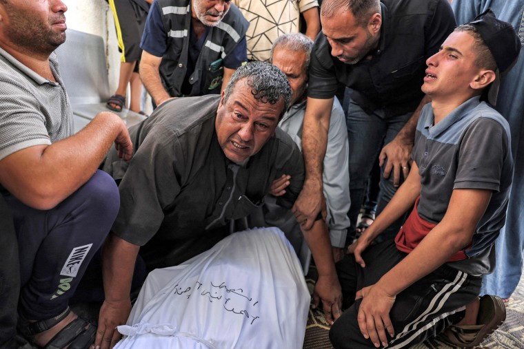 People mourn by the wrapped bodies of Palestinians killed in an Israeli airstrike during their funeral in Rafah in the southern Gaza Strip on Oct. 13, 2023. 