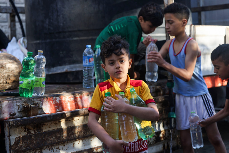 Children fill bottles with water from a mobile cistern in Gaza.