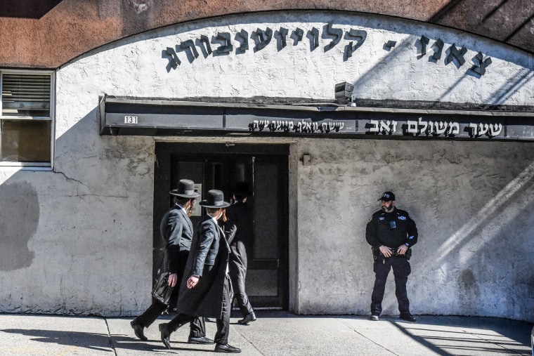An NYPD officer patrols in front of a synagogue in Brooklyn.