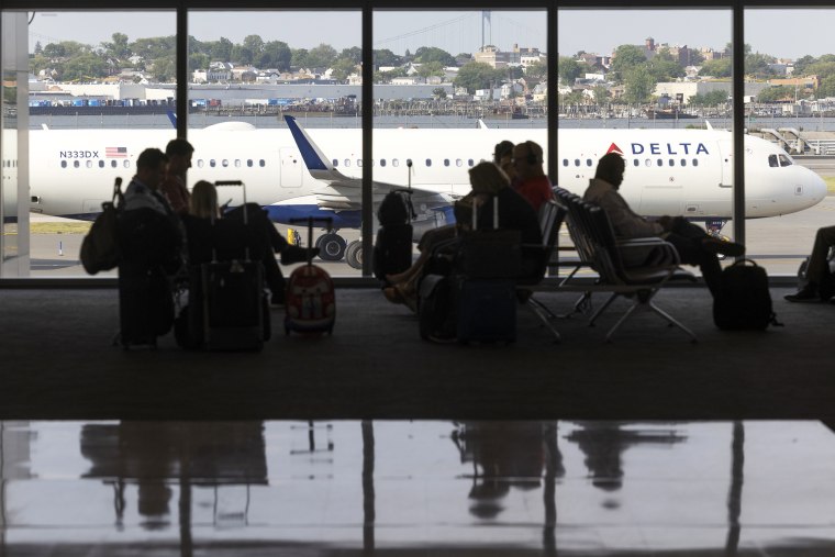 Passengers at a Delta gate with an airplane outside at LaGuardia Airport 