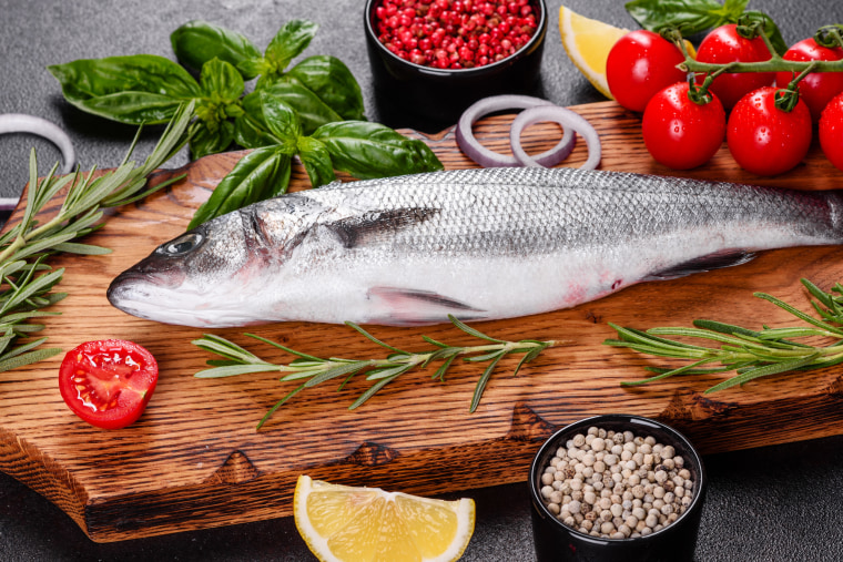 Fresh fish seabass and ingredients for cooking. Raw fish seabass with spices and herbs on a dark table