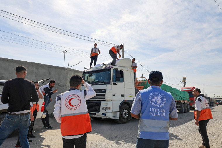 Volunteers gather around trucks carrying humanitarian aid that entered the Gaza Strip from Egypt via the Rafah border crossing on Oct. 21, 2023. 