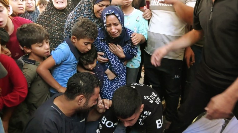 Muna Habil and others look at bodies recovered from the rubble.