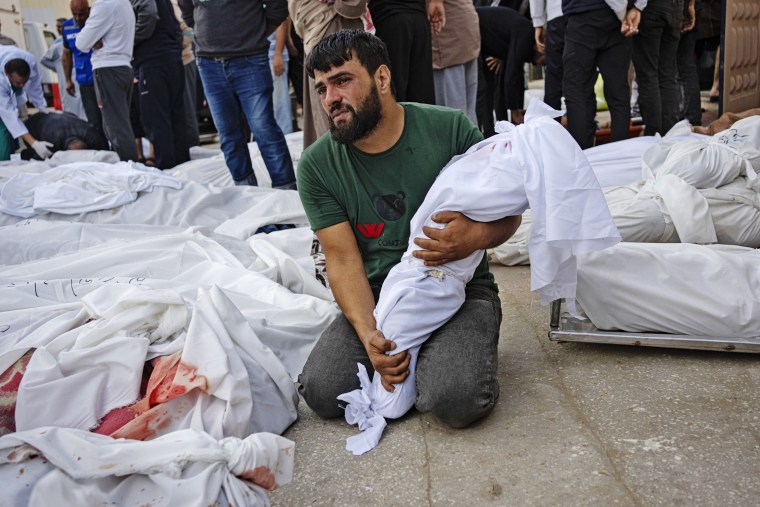 A father holds his child's body next to others killed in the Israeli bombardment of the Gaza Strip at Al-Aqsa Hospital in Deir Al-Balah, central Gaza, on Sunday, Oct. 22, 2023.