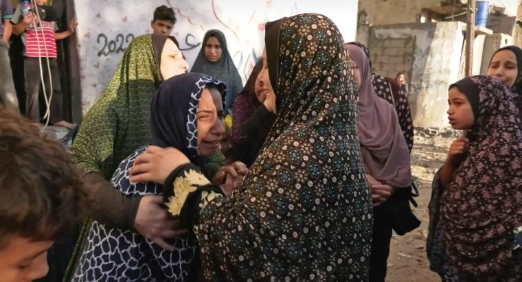 Muna Habil, in blue, is comforted by other women. 