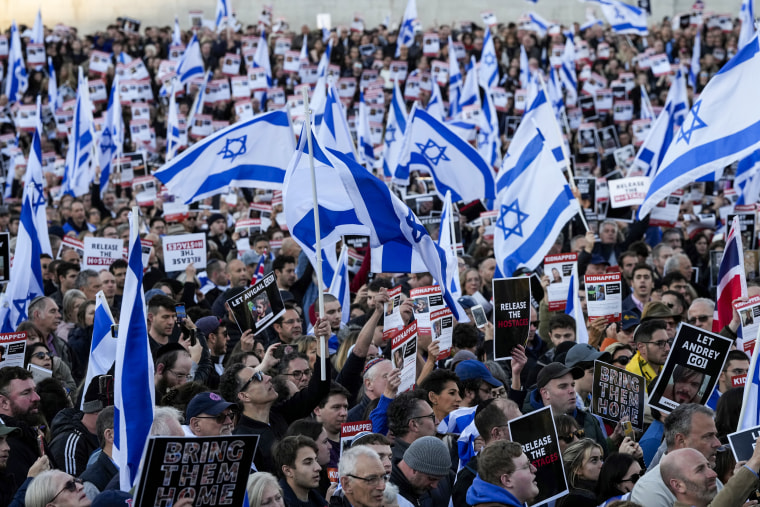 People carry Israeli flags and pictures of people believed taken hostage and held in Gaza, during a protest in London.
