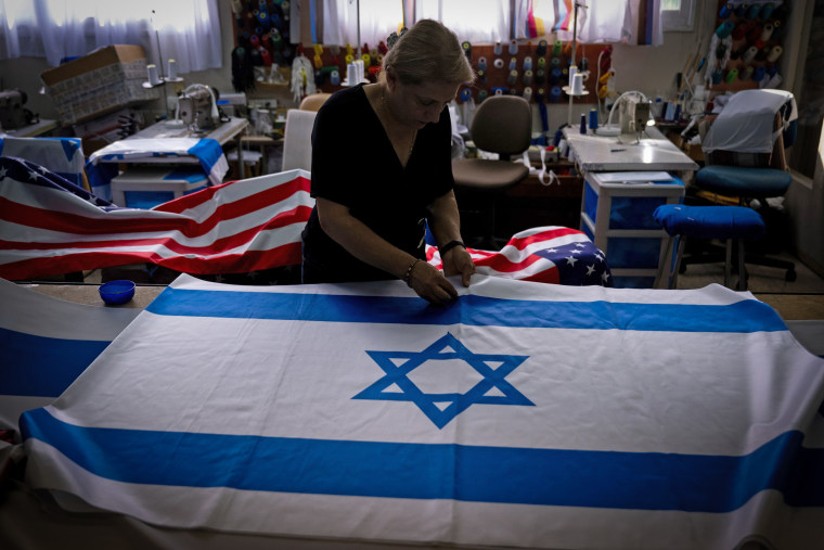 A seamstress pins an Israeli flag before sewing it at the Marom factory on Oct. 22, 2023 in Kfar Saba, Israel. The factory is running 24 hours a day since the war began two weeks ago, manufacturing thousands of flags of all sizes for funerals, state visits, government offices, and the military.