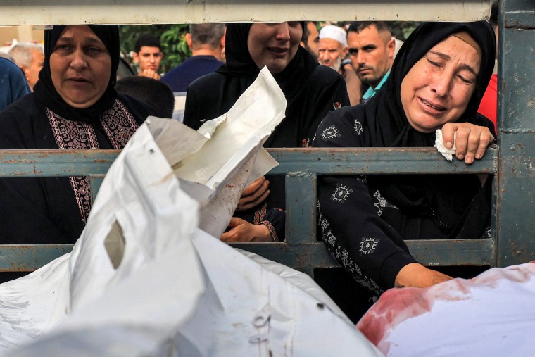 People mourn next to a truck carrying the dead before their funerals outside the morgue at Nasser Hospital in Khan Younis, Gaza.